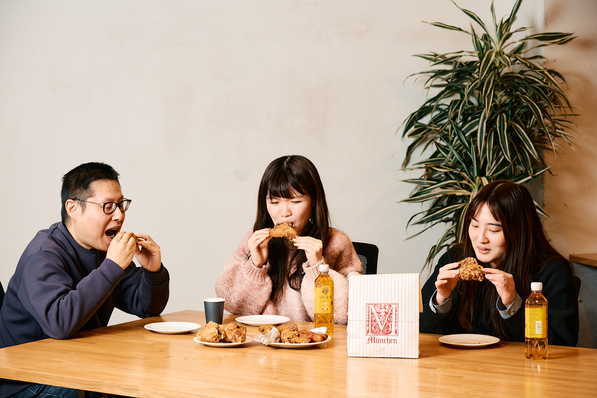 テーブルでみゅんへんの唐揚げを楽しむ3人のモデル写真